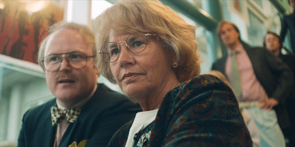 a woman wearing glasses sits next to a man wearing a bow tie