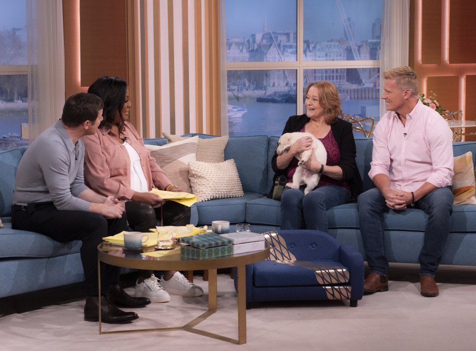 a group of people sitting on a couch with a woman holding a dog