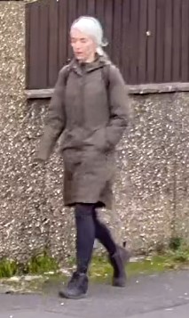 a woman in a parka is walking down the street .