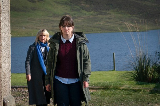 two women are walking in front of a lake