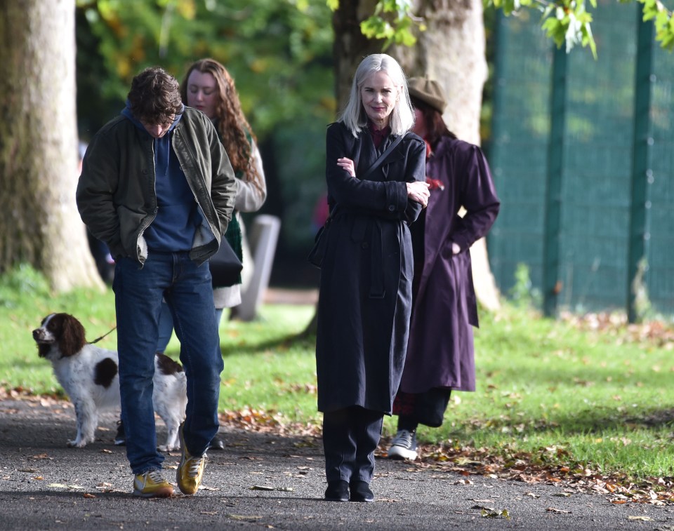 a group of people walking a dog in a park