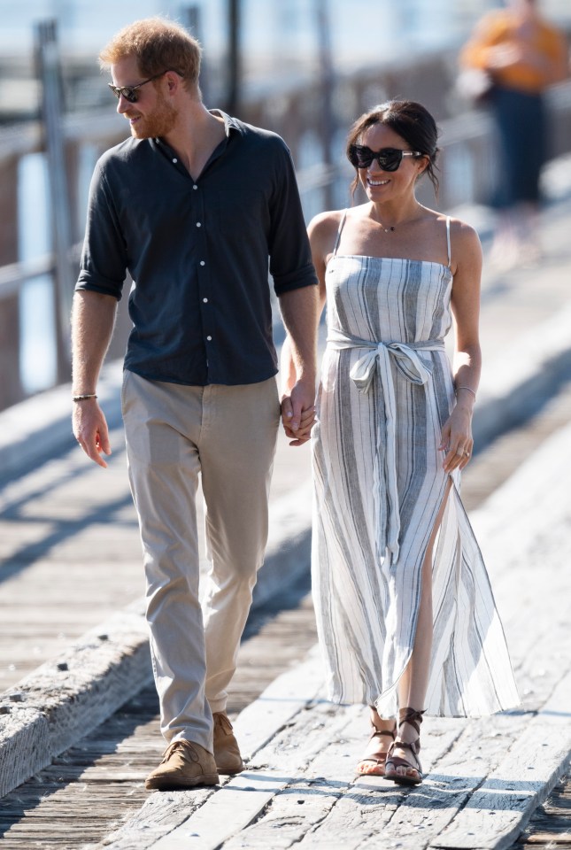 a man and a woman are walking on a pier holding hands