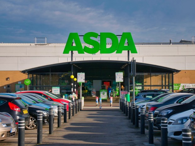 Birkenhead, UK - Nov 6 2020: The car park, entrance and green sign of a store of the ASDA British supermarket chain, located in a residential area in the North of England. Taken on a sunny day in autumn with a blue sky in the background.