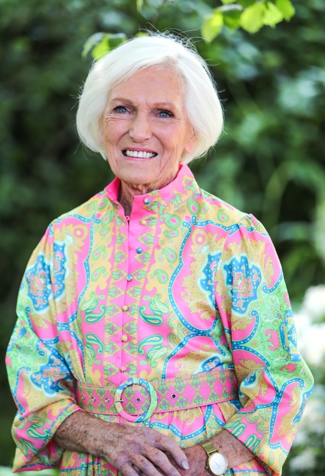 an elderly woman wearing a colorful dress and a watch smiles for the camera