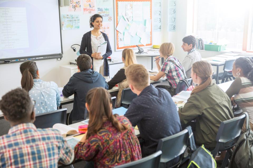 a teacher stands in front of a classroom full of students