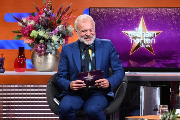 a man in a blue suit sits in front of the graham norton show