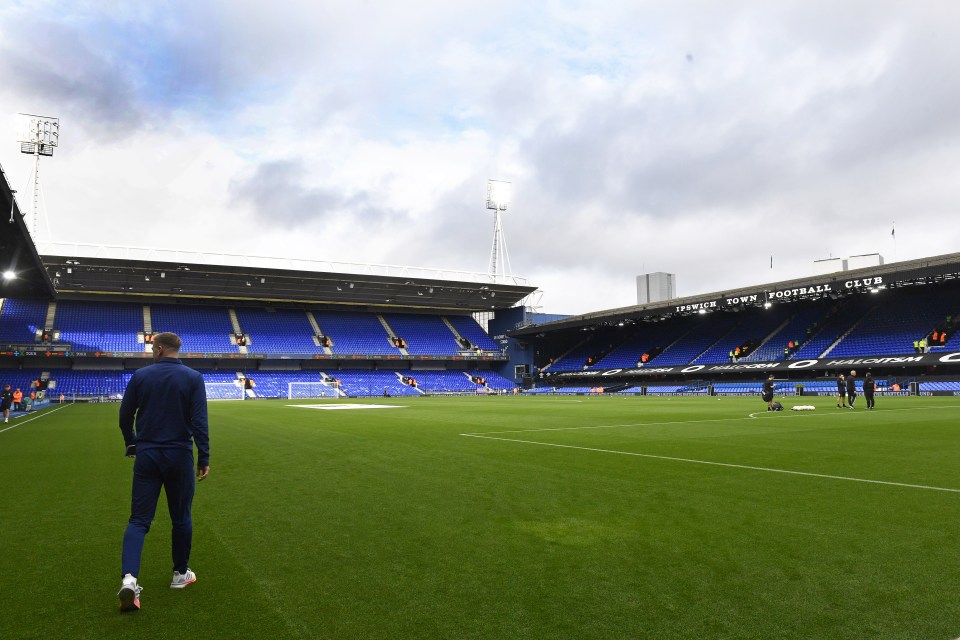 a man walking on a soccer field with a sign that says town football club