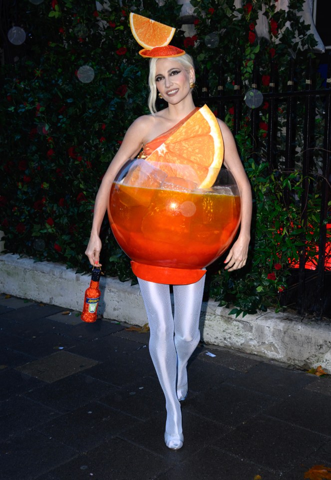 a woman dressed as an orange is holding a bottle