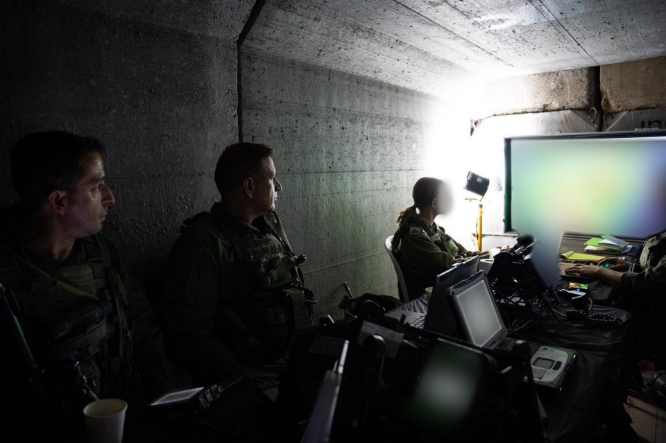 a group of soldiers are sitting in a dark room using laptops