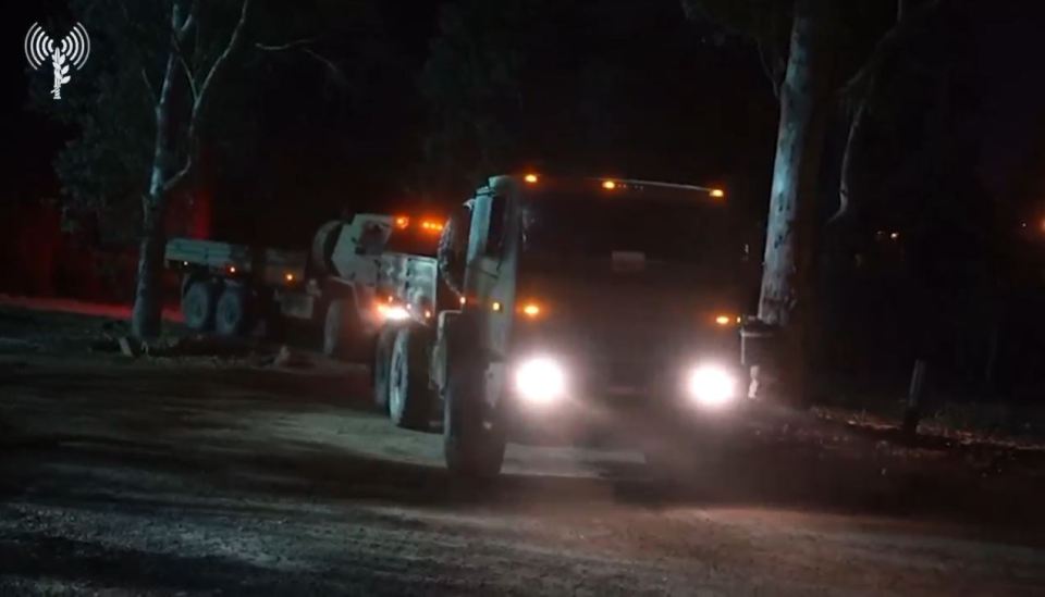 a military truck is driving down a dirt road at night