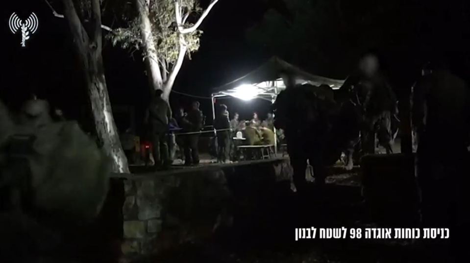 a group of people are gathered under a tent at night