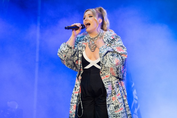 a woman singing into a microphone wearing a jacket that says ' nirvana ' on it