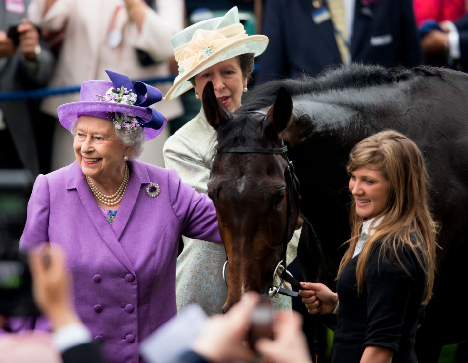 queen elizabeth ii in a purple jacket stands next to a horse