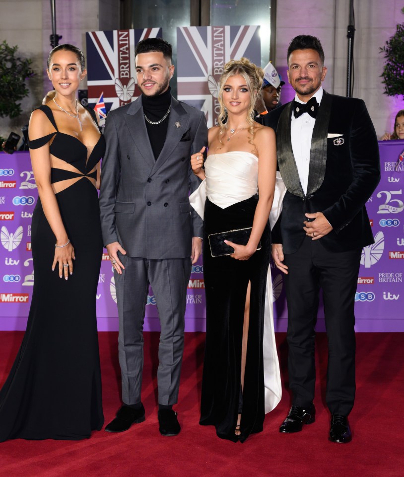 a group of people standing on a red carpet with britain written on the wall behind them