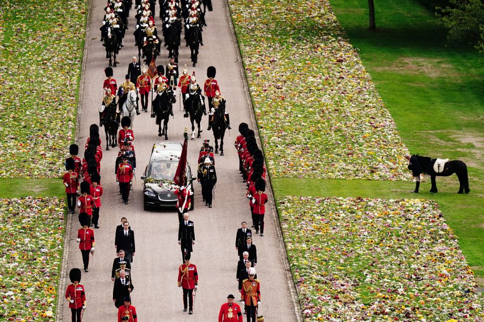 a funeral procession is going down a road lined with flowers