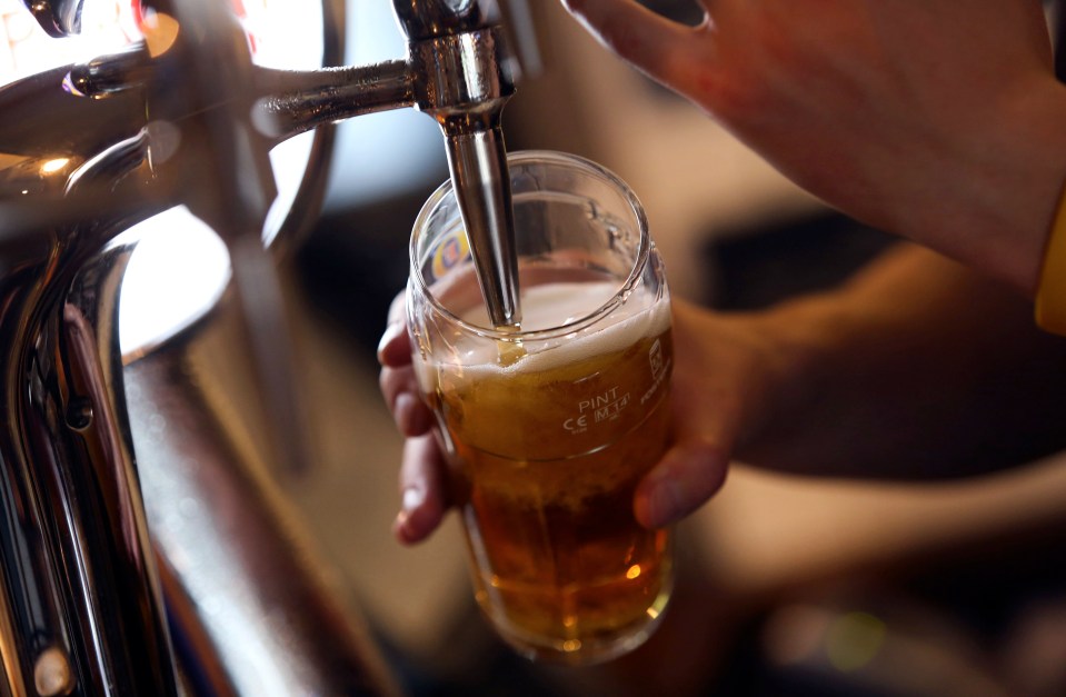 a person is pouring beer into a pint glass