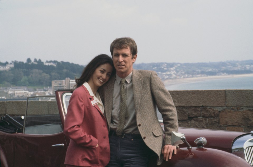 a man and a woman are posing for a picture in front of a car