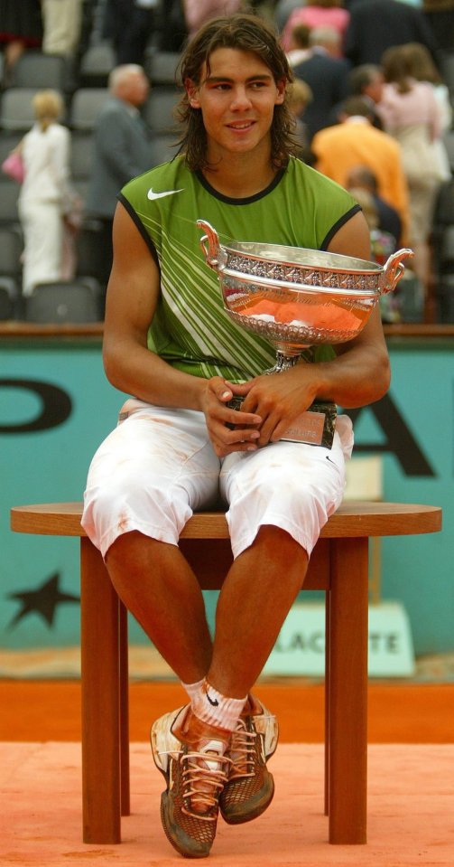 a man in a green nike shirt sits on a table holding a trophy