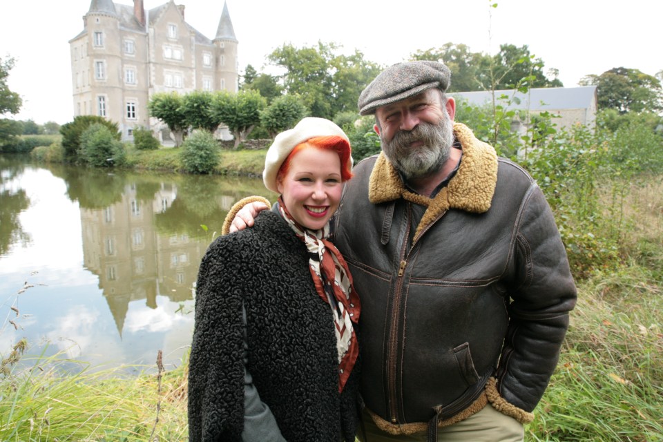 a man and a woman standing in front of a castle