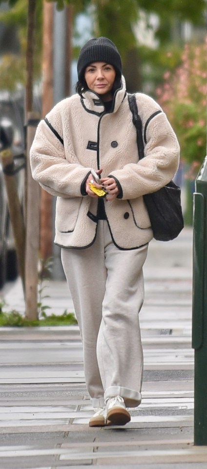 a woman wearing a beanie and a jacket is walking down the street