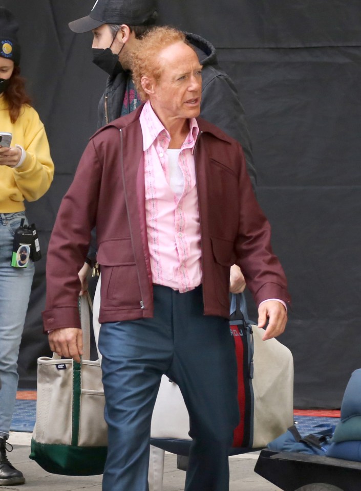 a man in a maroon jacket is carrying a canvas tote bag