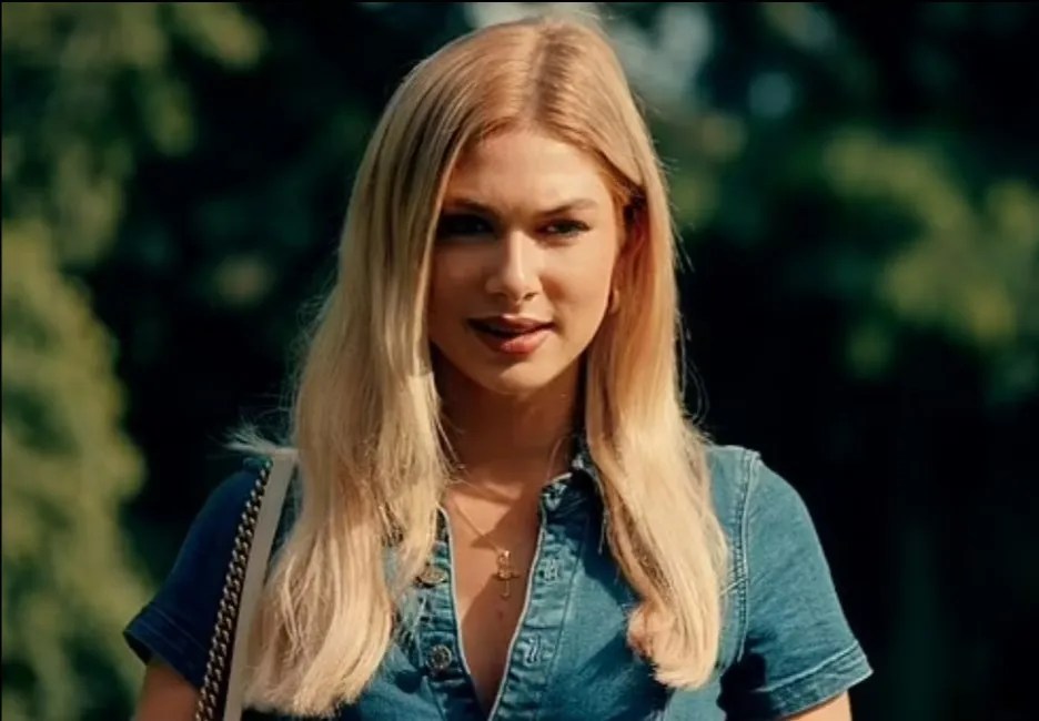 a blonde woman wearing a denim shirt and a cross necklace