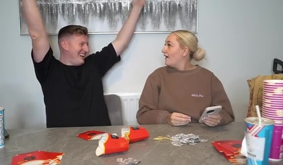 a man and woman sit at a table playing monopoly