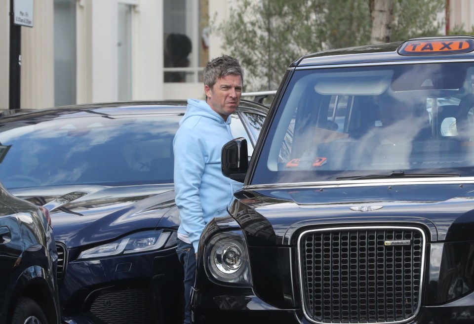 a man stands in front of a black taxi with a license plate that says ll19 kyj