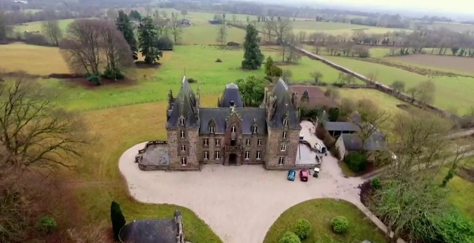 a large castle sits in the middle of a lush green field