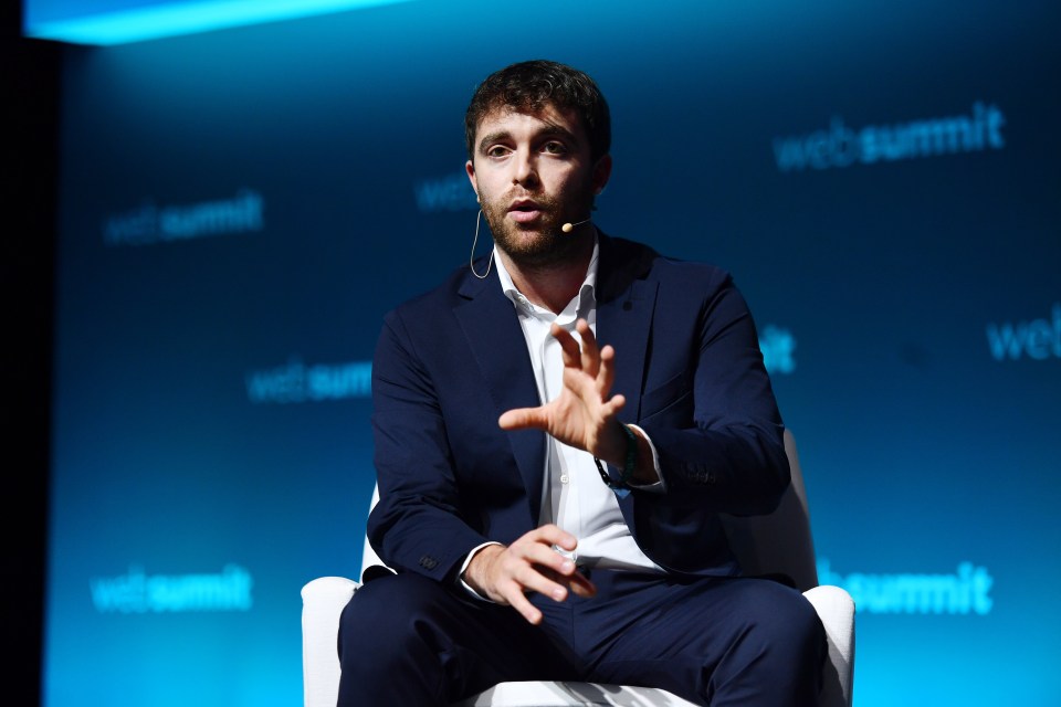 a man in a suit is sitting in front of a web summit sign