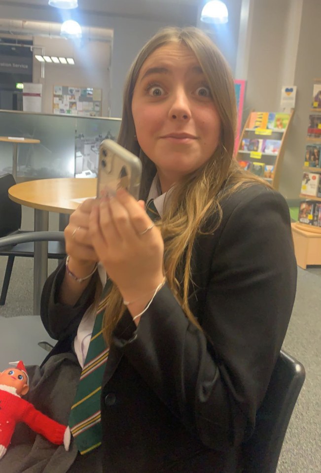 a girl in a school uniform is looking at her phone