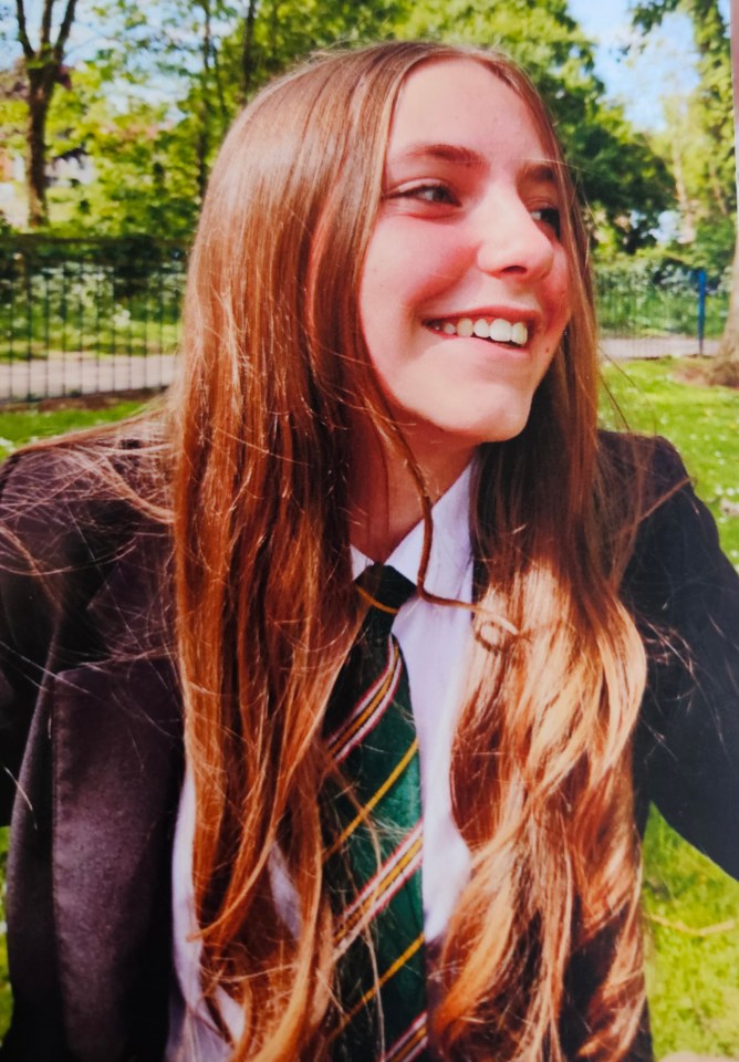 a girl in a school uniform and tie smiles for the camera