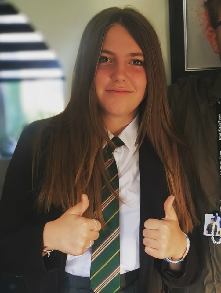 a girl in a school uniform giving a thumbs up