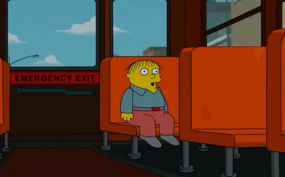 a cartoon character sits in an orange seat in front of an emergency exit sign