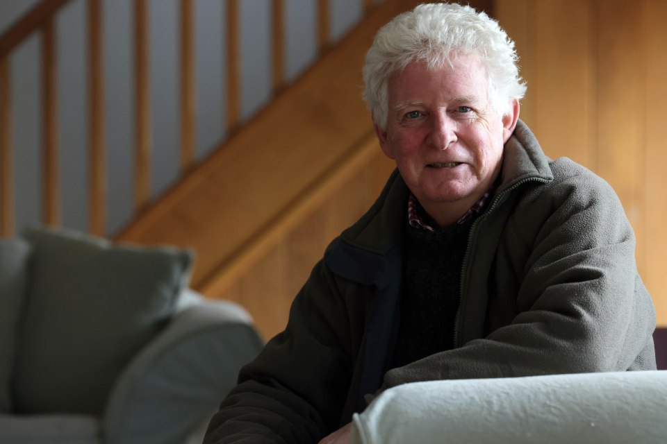 a man sitting on a couch with stairs in the background