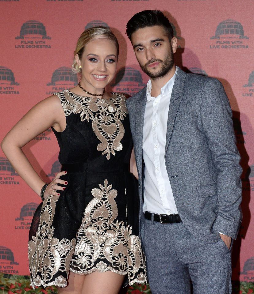 a woman in a black dress and a man in a suit pose on a red carpet that says films with live orchestra