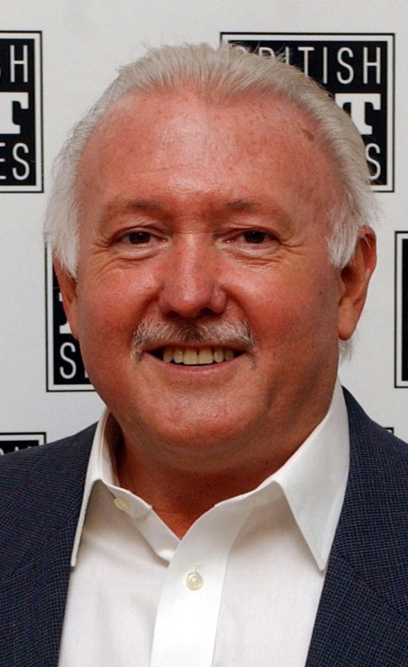 a man is smiling in front of a sign that says british