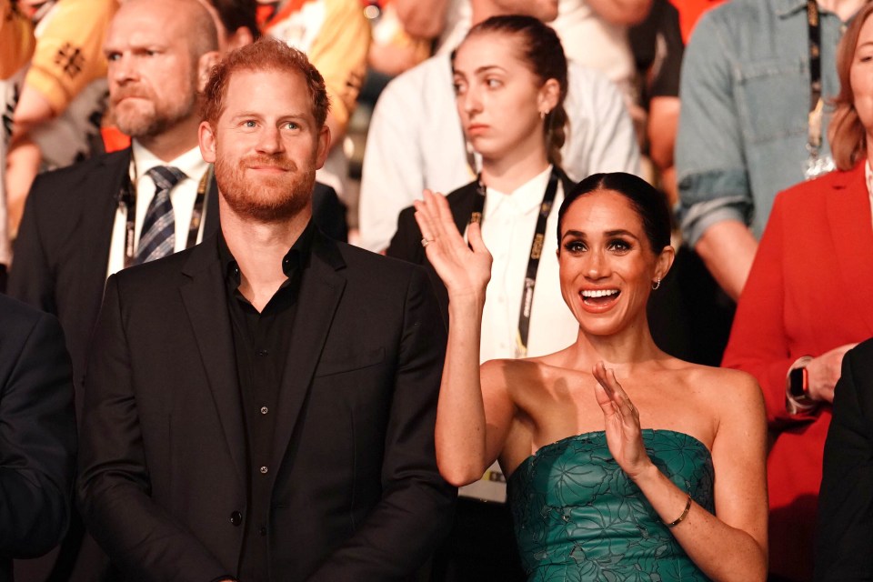 a man in a suit and a woman in a green dress are sitting in a crowd