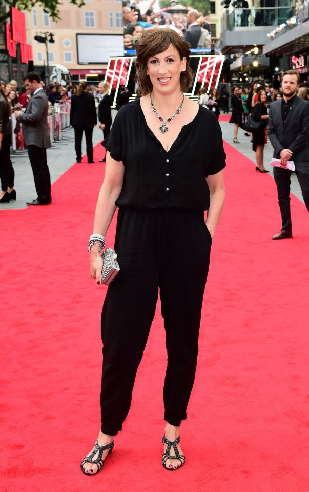 a woman in a black jumpsuit stands on a red carpet