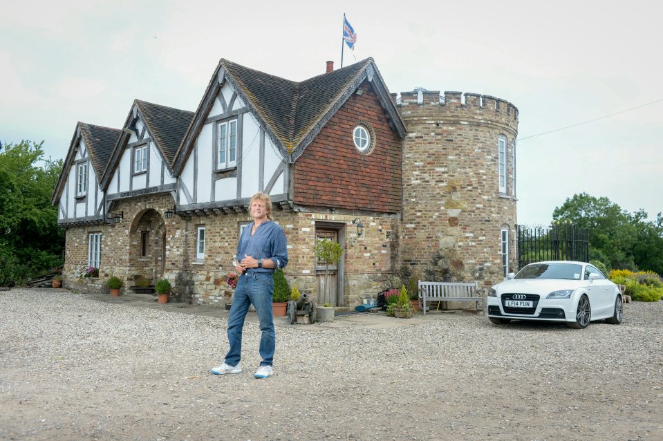 a man stands in front of a brick house with an audi parked in front of it