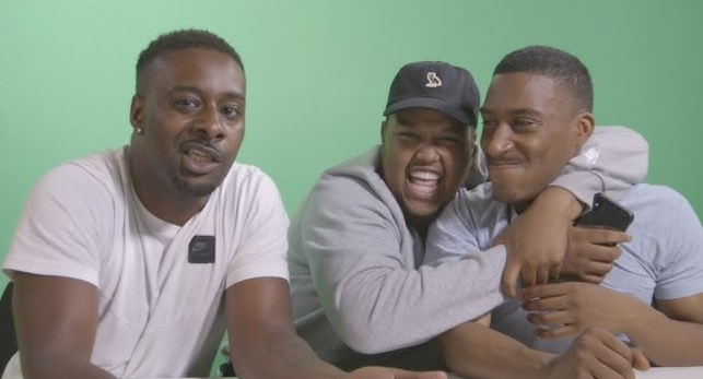 three young men are sitting at a table with their arms around each other .