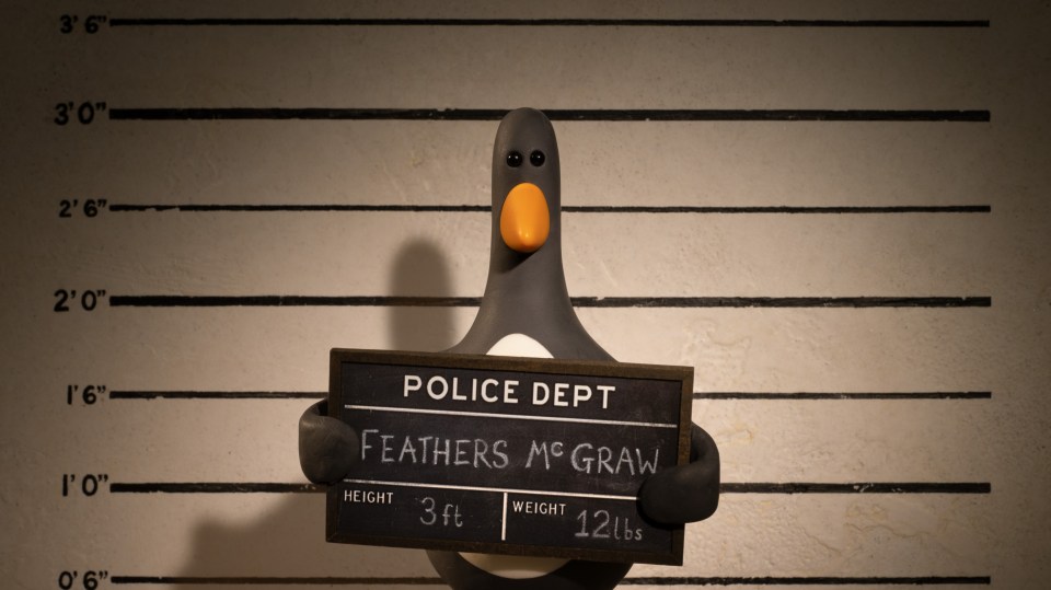 a penguin holding a police dept sign that says feathers mc graw