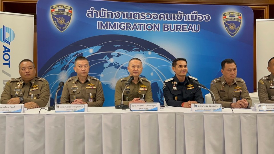 a group of men sit at a table in front of a sign that says immigration bureau