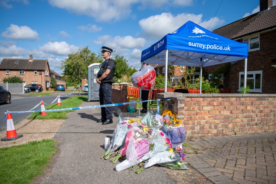 Flowers and police outside of the home in August last year