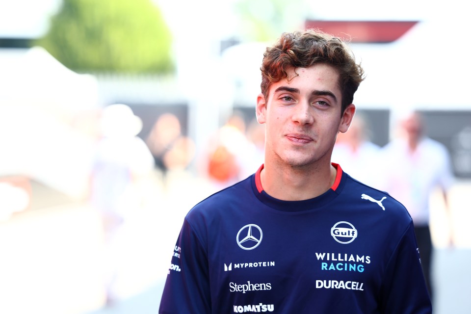 a young man is wearing a williams racing shirt