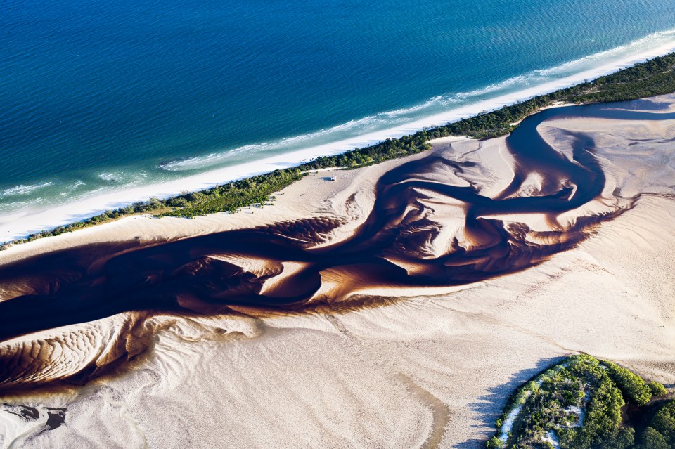 an aerial view of a river flowing through a sandy area