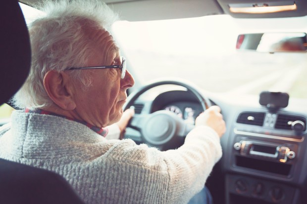 an older man wearing glasses is driving a car