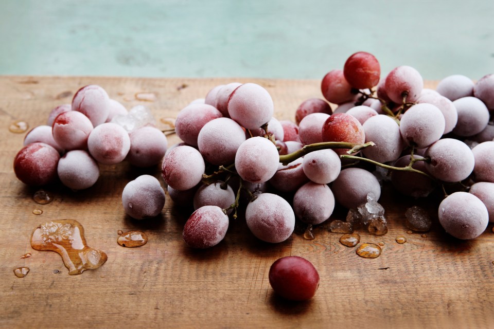 a bunch of frozen grapes on a wooden table