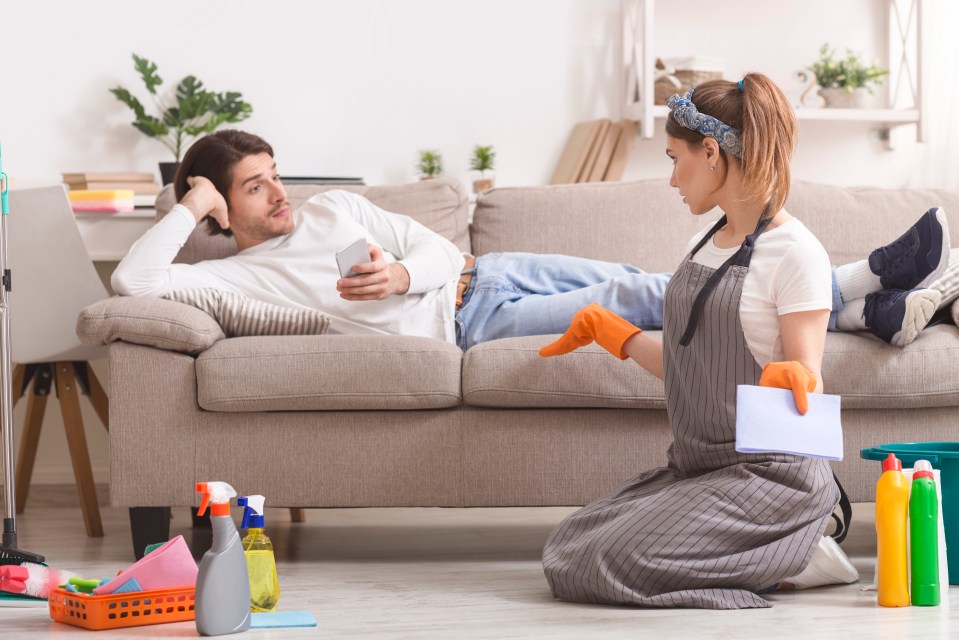 a man laying on a couch while a woman sits on the floor cleaning