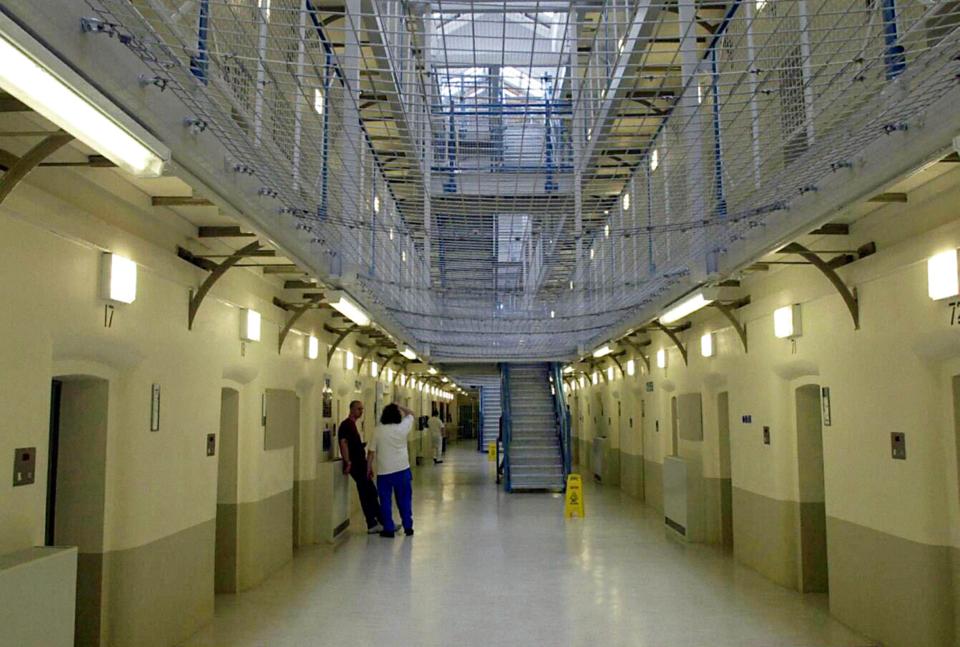 a prison hallway with a yellow wet floor sign